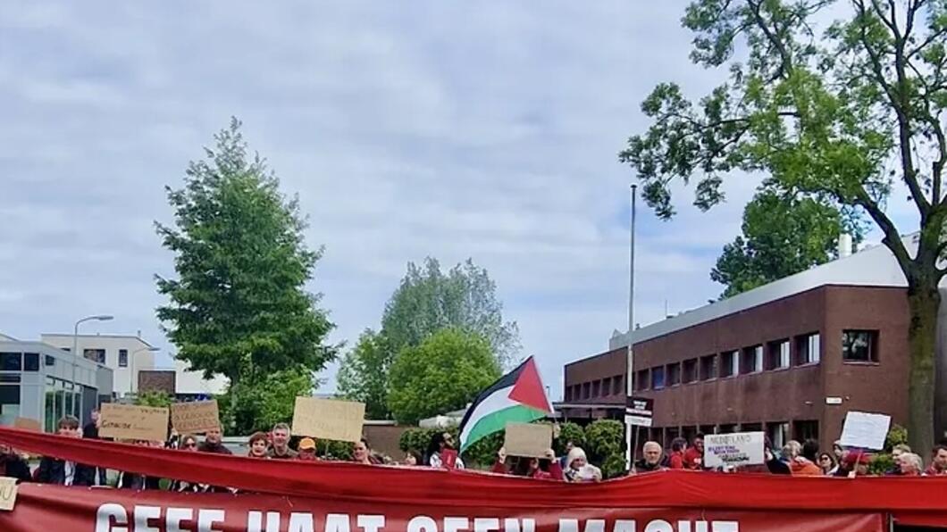 Foto van een rij mensen met daarvoor een rode banner waarop geschreven staat ‘geef haat geen macht’