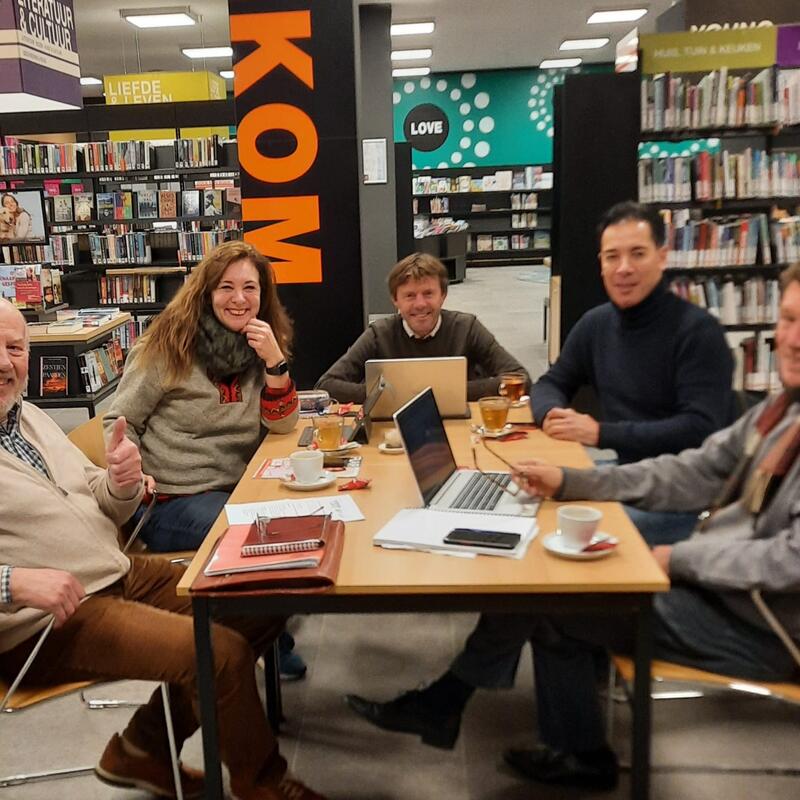 Aftrap gezamenlijk redactieteam GroenLinks/PvdA - 4 witte mannen en 1 vrouw tussen boeken van bibliotheek Lunteren