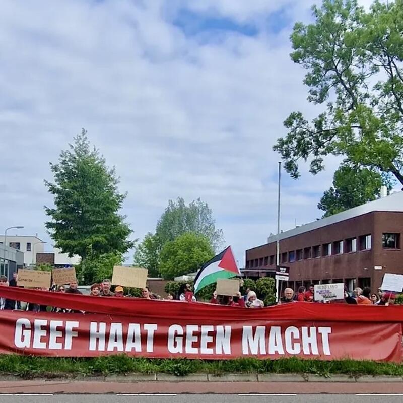 Foto van een rij mensen met daarvoor een rode banner waarop geschreven staat ‘geef haat geen macht’