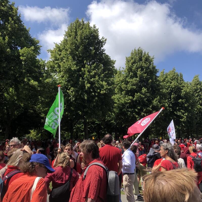 In rood geklede mensenmassa, met in de achtergrond een groene en een rode vlag.