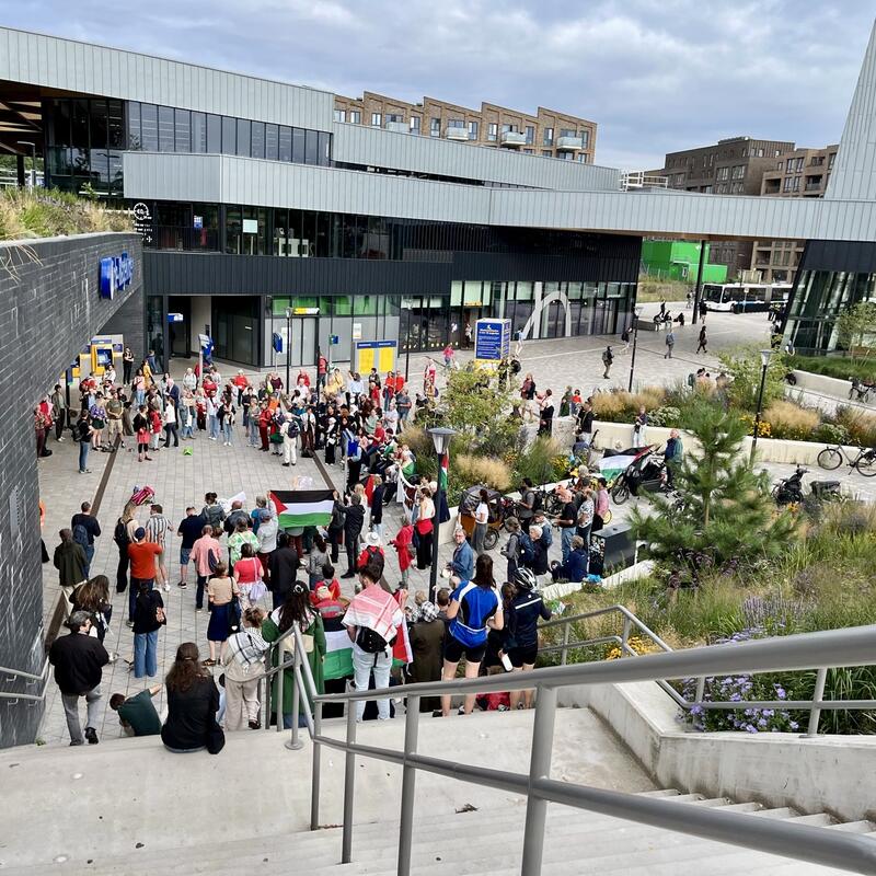 Vanaf boven aan de trap gemaakte foto van groep mensen die deelnemen aan lawaaiprotest.