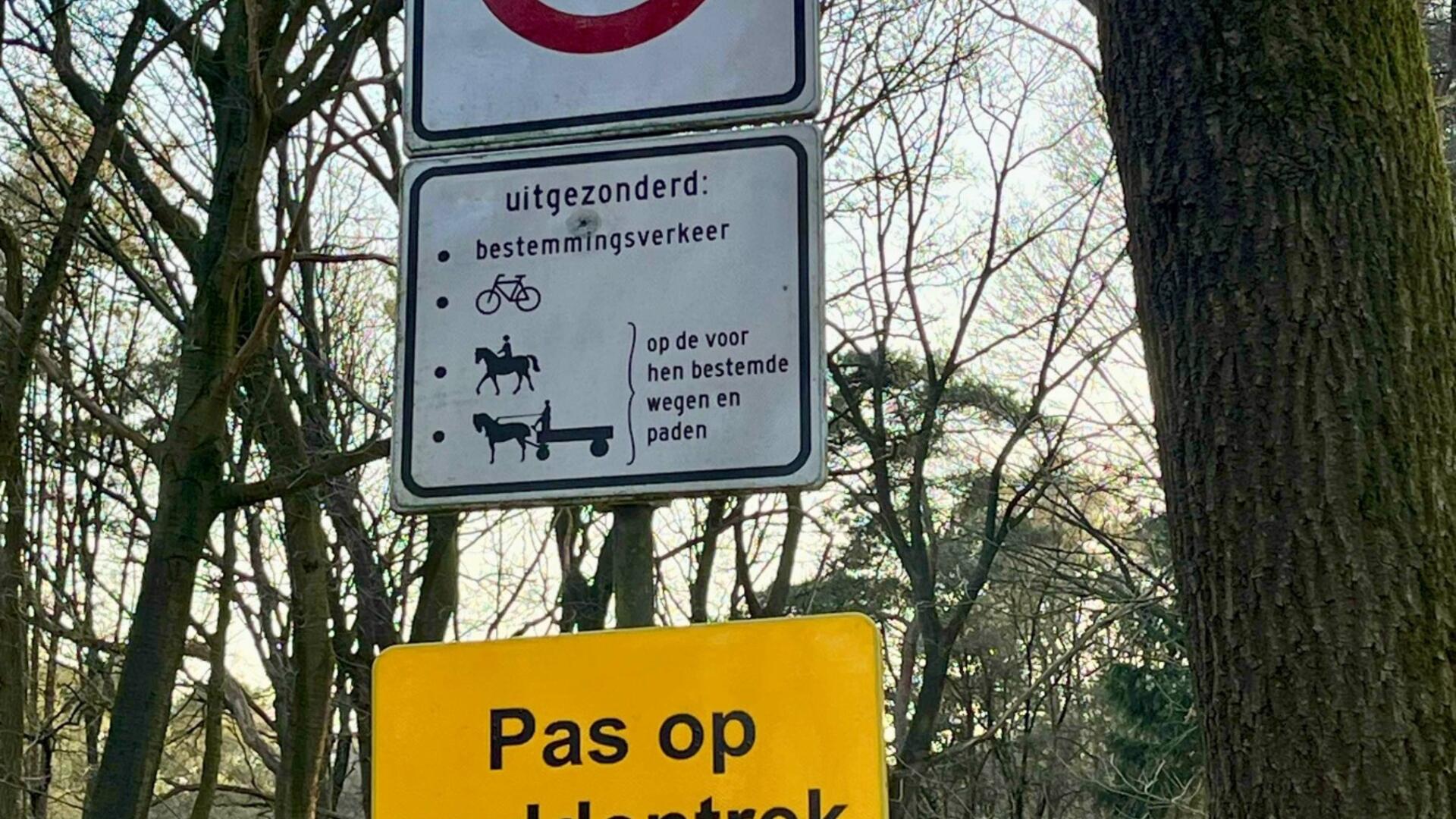 Bospad met een bord ernaast, het onderste bordje is geel met opschrift ‘let op, paddentrek’. 